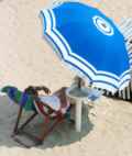 Mann am Strand im Liegstuhl mit Sonnenschirm