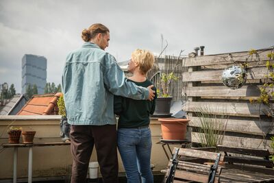 Erwachsener Mann legt Seniorin Hand auf die Schulter.
