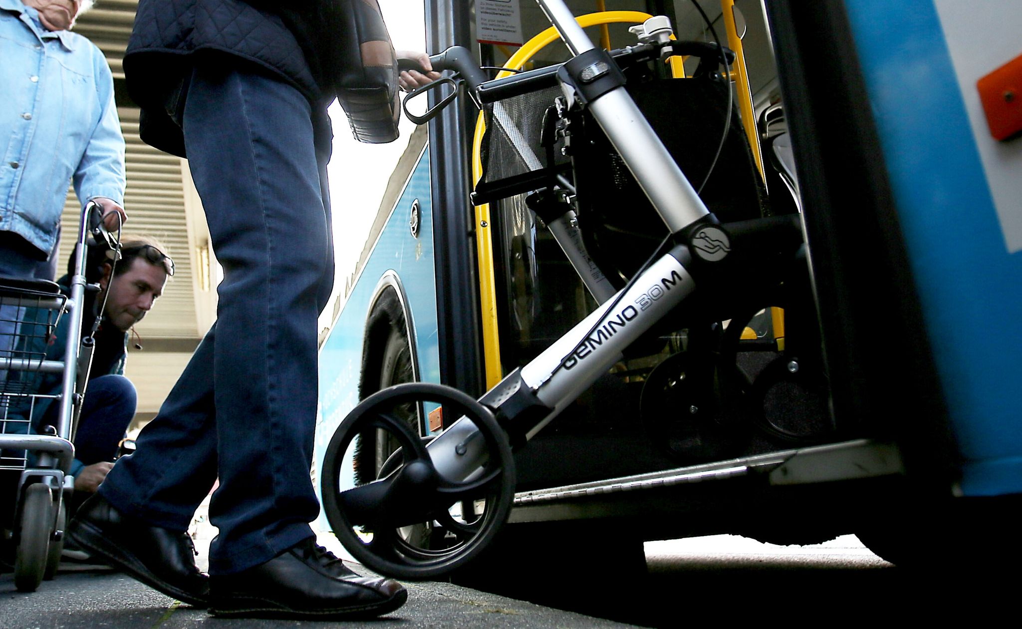 Jemand steigt mit einem Rollator in einen Bus ein.