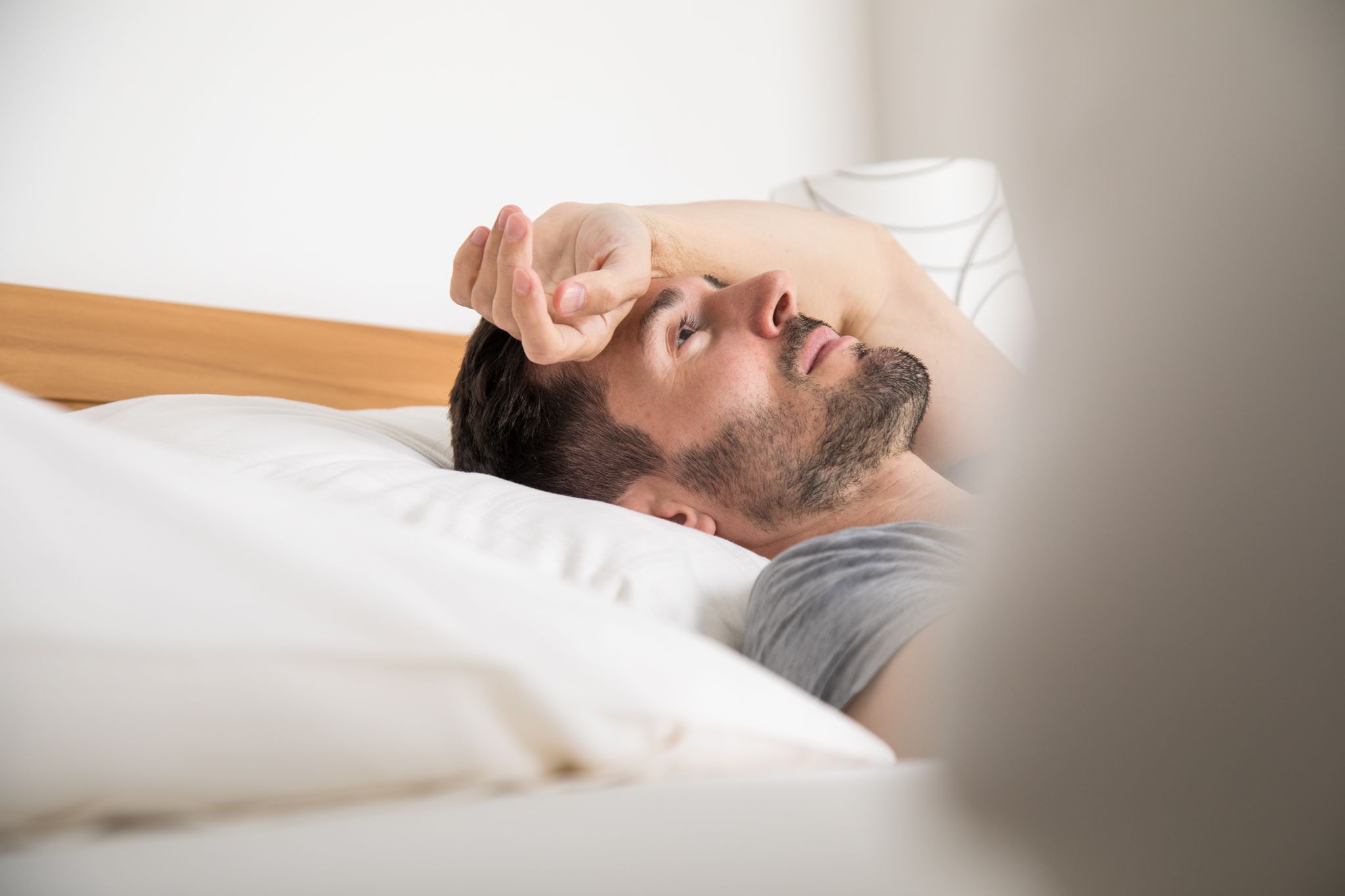 Mann liegt schlaflos im Bett