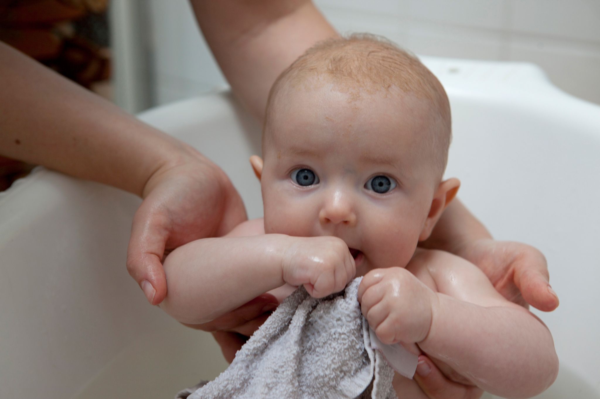 Person hält Baby in Badewanne