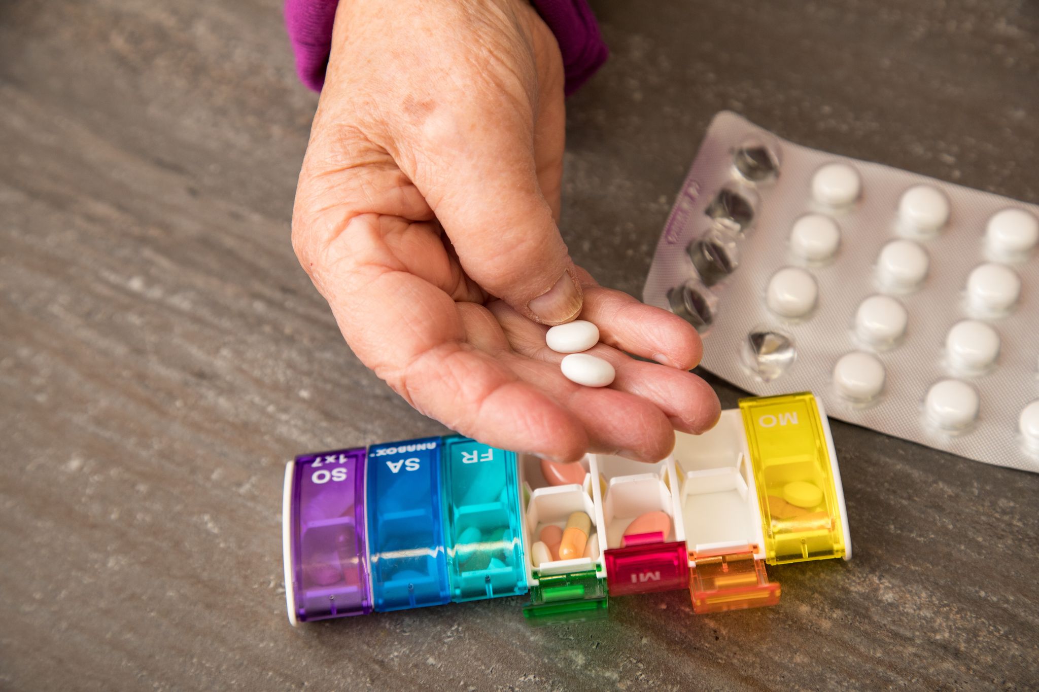 Seniorin nimmt Tabletten aus einer Pillendose