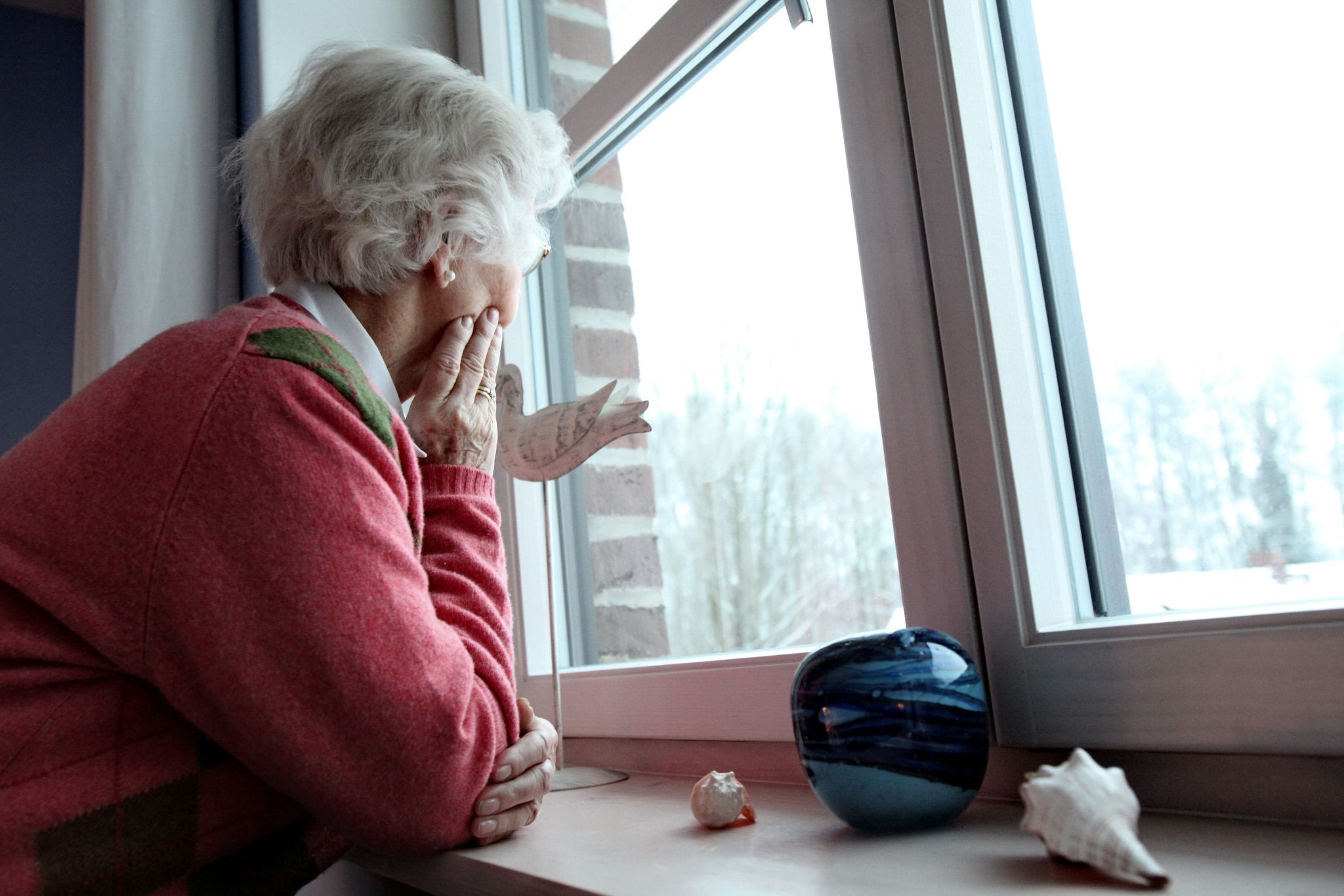 Eine Seniorin schaut aus dem Fenster