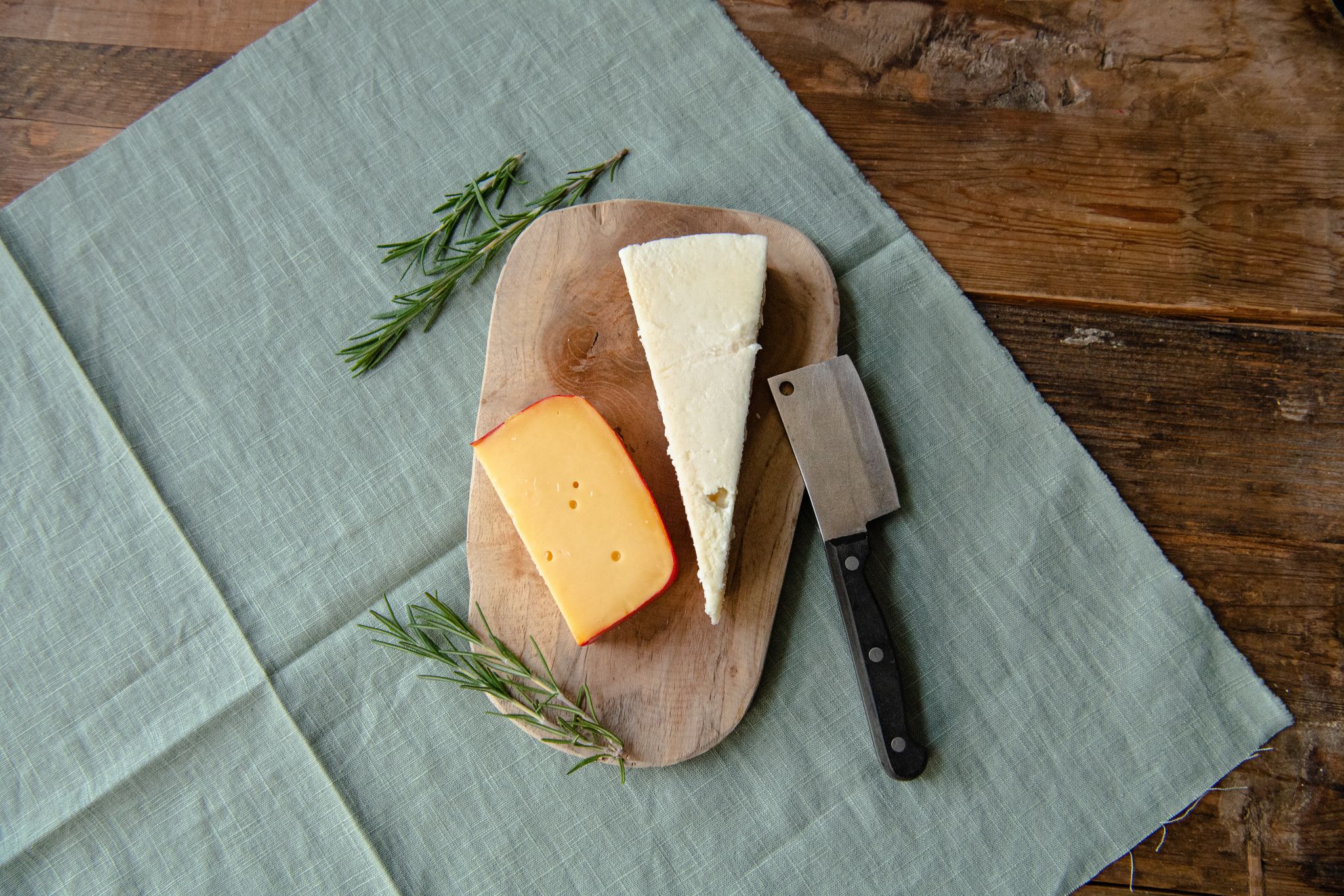 Gouda (l) und Parmesan liegen auf einem Holzbrett