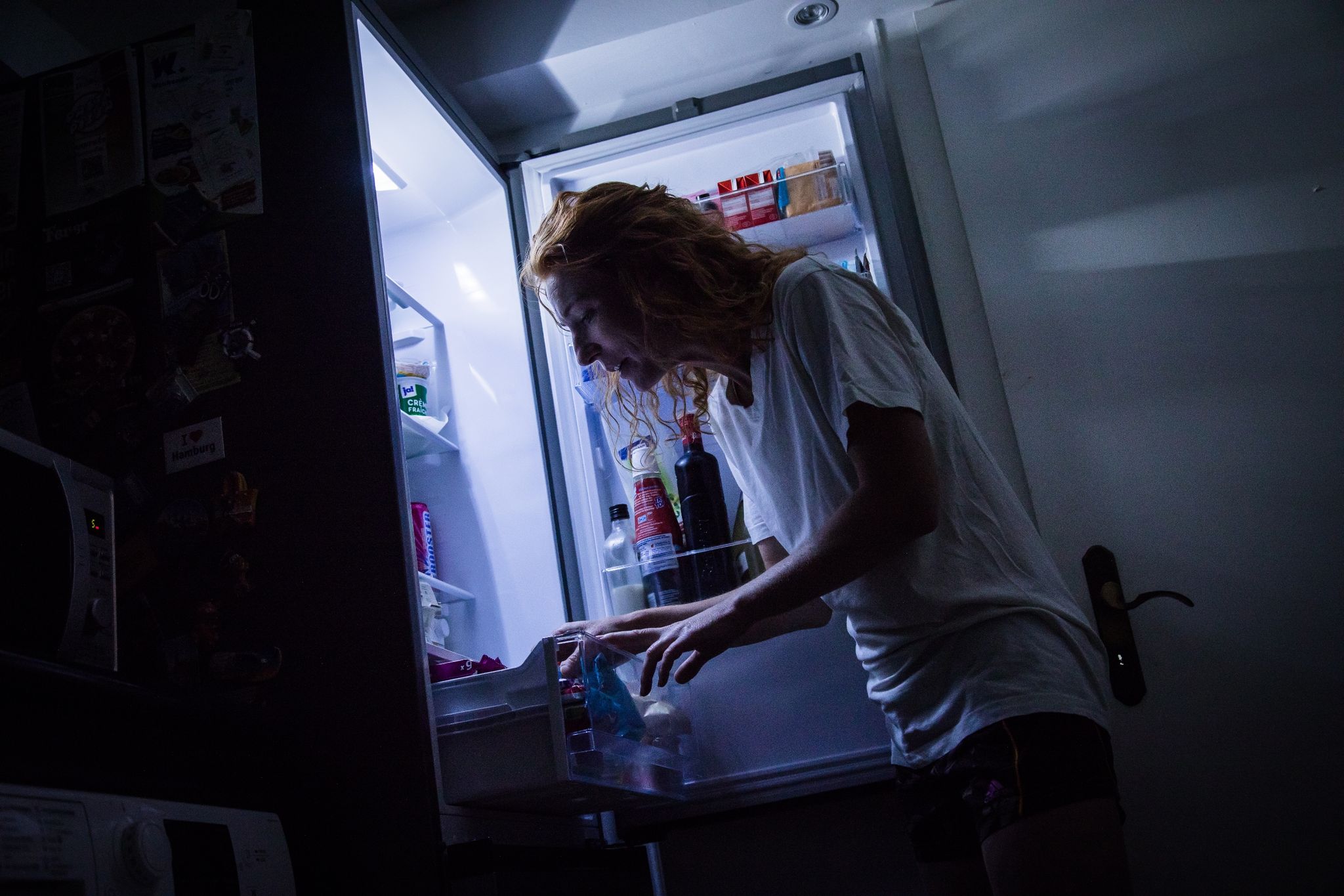 Eine Frau geht nachts an den Kühlschrank