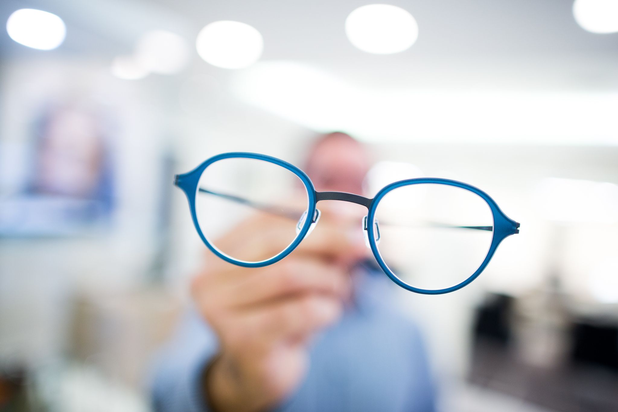 Optiker hält eine Brille in der Hand