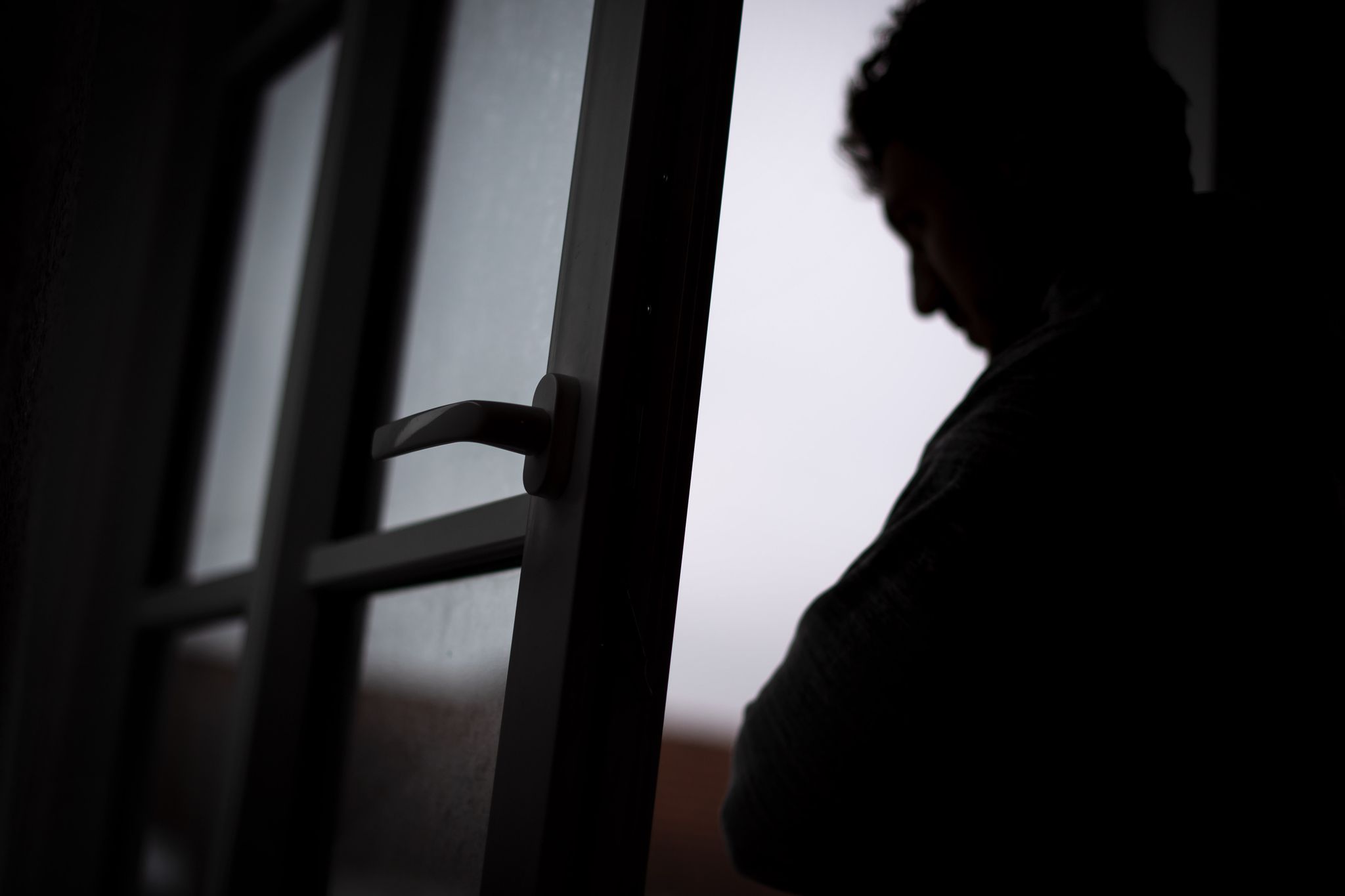 Eine Person steht im Gegenlicht am Fenster